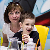 Наталія Кузьміна сидить на стільці у кафе з дитиною на руках